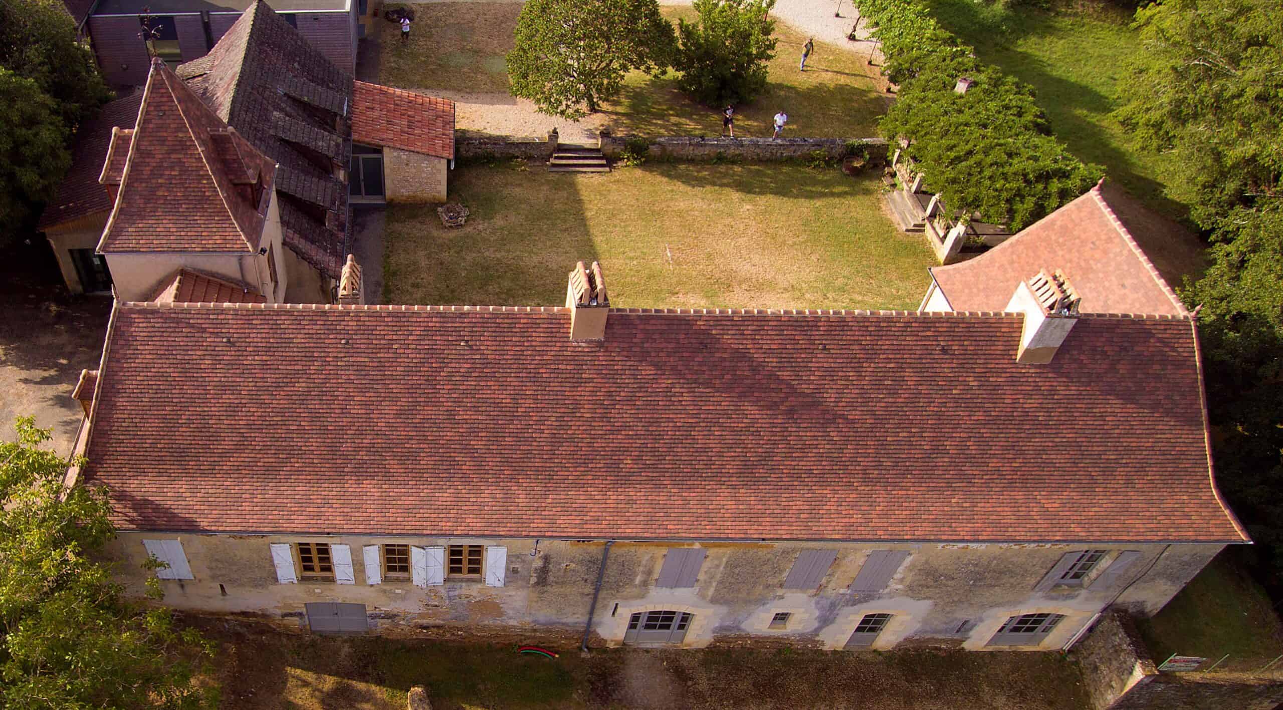 Detail of Detail of Gabarre blend French shingle tiles with natural texture and mossy tones along the eaves of a traditional French-style chateau.