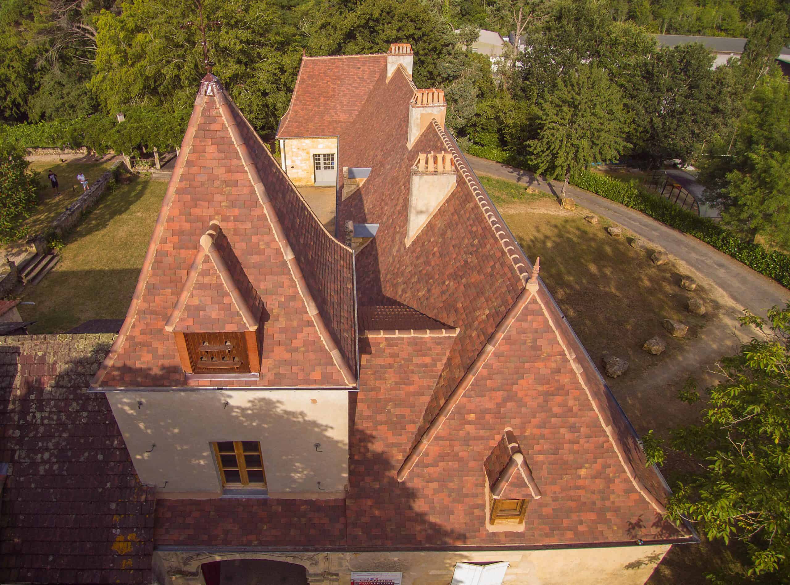 French chateau with Edilians Gabarre blend 20x30 clay shingle tiles on the main roof, showing rich reds and browns with a textured old-world finish