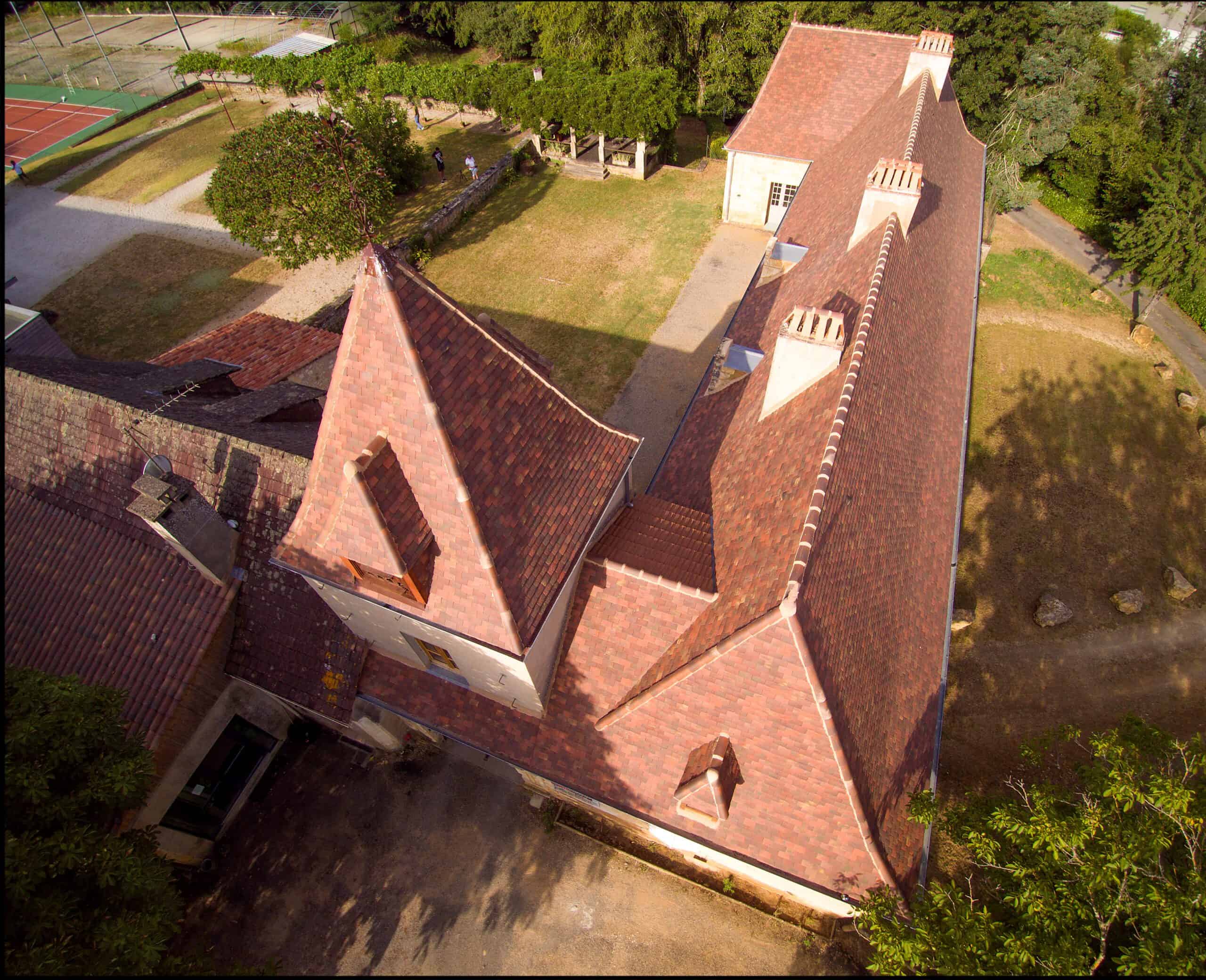 Angled view of French chateau turret roof with 20x30 clay tiles in Gabarre blend, highlighting color variation and authentic texture.